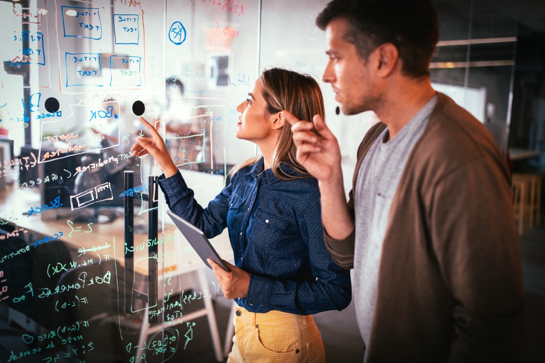 Professionals analyzing competitive landscape on glass board